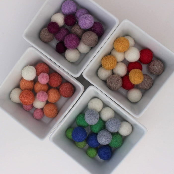 Felt balls divided into colours, purples, pinks, greens or reds. 